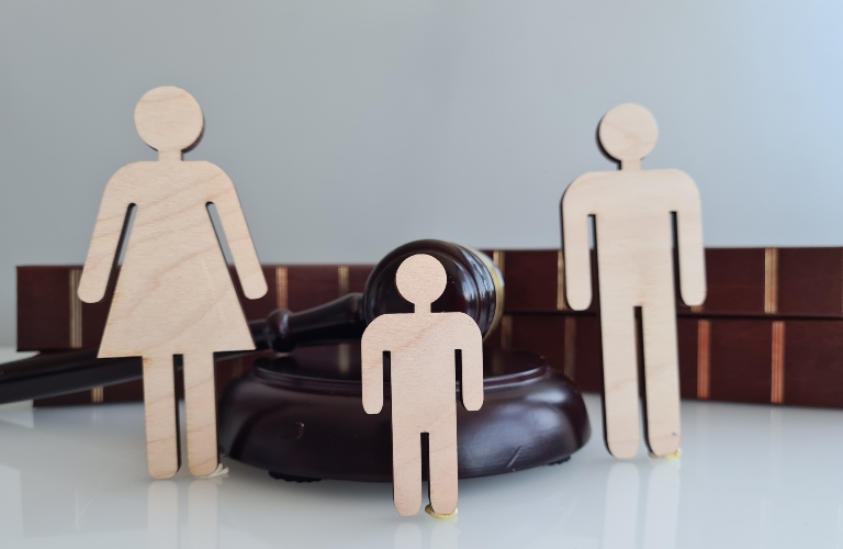 Wooden figures representing a family near a gavel and law books