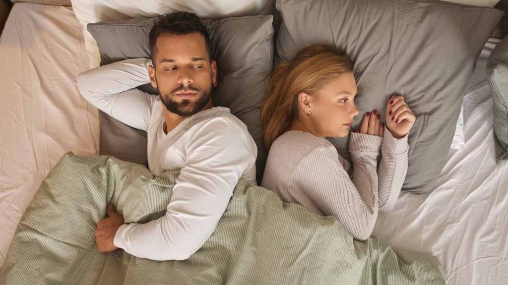 Displeased couple lying back to back on a bed and ignoring each other
